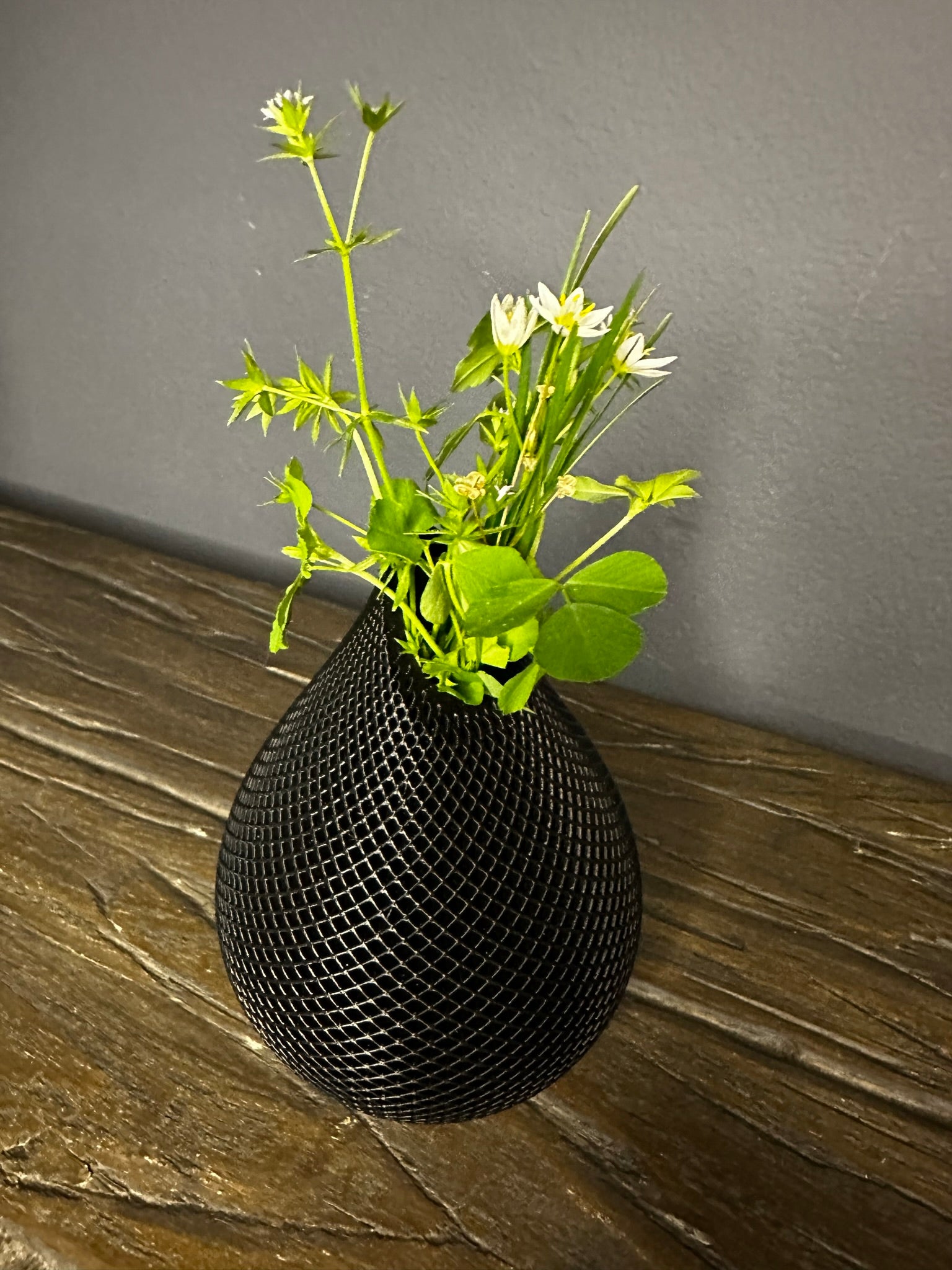 Photo of Handmade 3D Printed Vase in Black Color with Mesh Pattern with some flowers inside