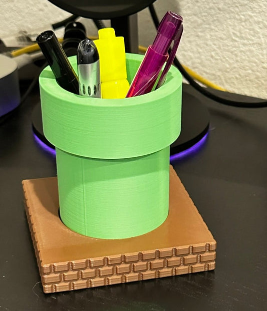 super mario brothers themed desk organizer pen pencil holder with a green pipe sitting on brown bricks