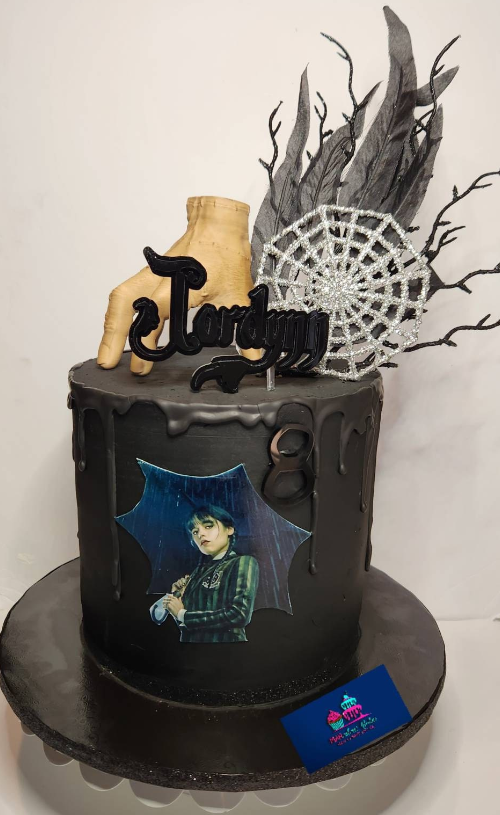photo of a black Wednesday Addams decorated birthday cake featuring the THING hand on top of the cake